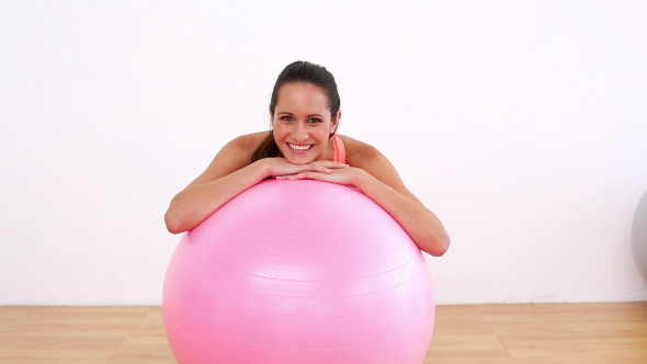 Fit Model Leaning On Pink Exercise Ball Smiling