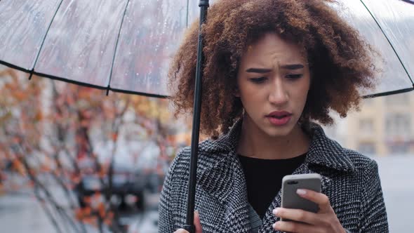 African American Woman Curly Girl with Transparent Umbrella Stands on Autumn Street in Rain Looks at alt