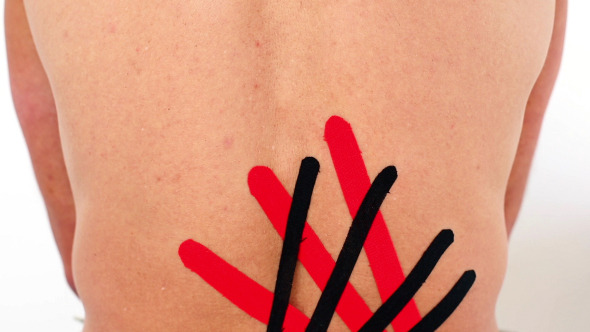 Red And Black Kinesio Tape Being Applied To Back