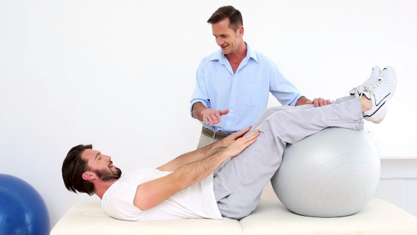 Physical Therapist Helping His Patient Do A Sit Up