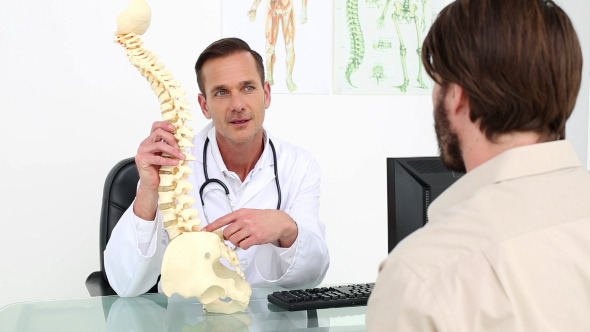 Doctor Showing His Patient A Model Of A Spine