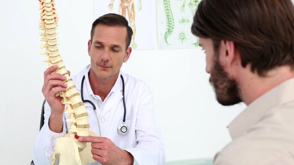 Doctor Showing His Patient A Spine Model