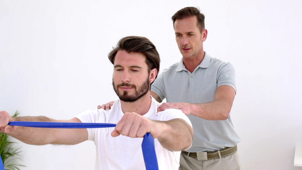 Physiotherapist Checking Patient Pulling A Band