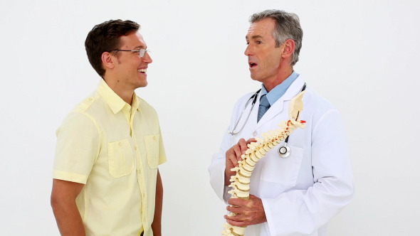 Doctor Holding Spine Model Talking To Patient