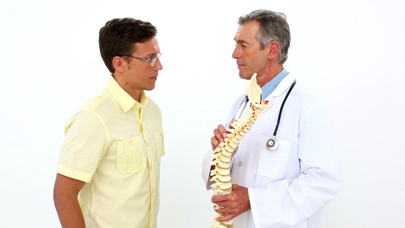 Doctor Holding Model Of Spine Talking To Patient