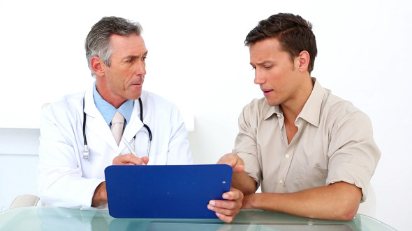 Patient Listening To His Doctor Holding Clipboard