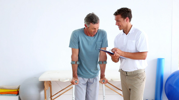 Physiotherapist Talking To Patient On Crutches 1