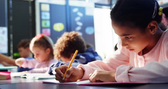 Attentive schoolgirl doing her homework in classroom alt