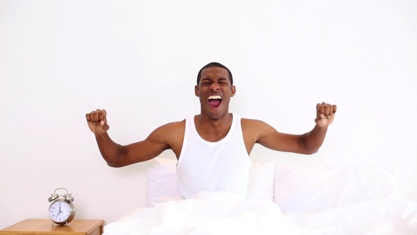 Happy Man Yawning And Stretching Sitting In Bed 1