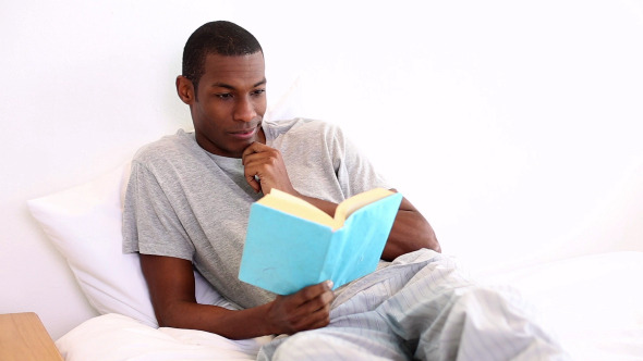 Relaxed Man Lying On Bed Reading