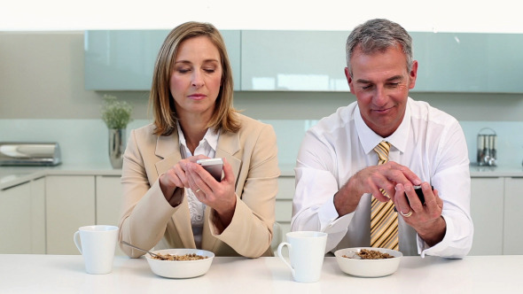 Couple Having Breakfast And Texting Before Work