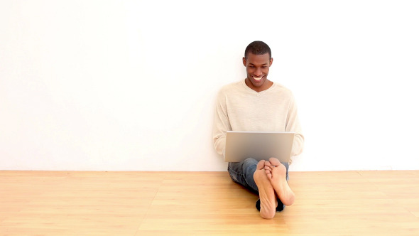Smiling Man Using Laptop Sitting On The Floor