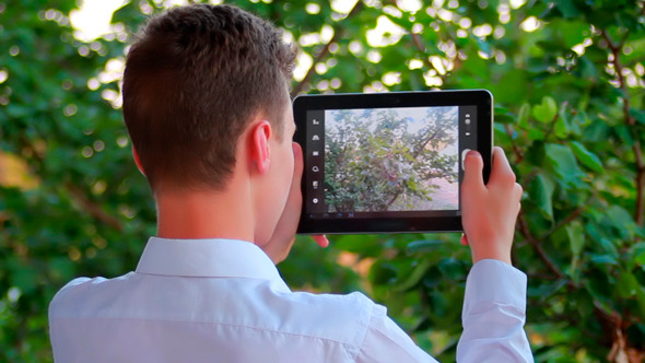 Teen Taking Pictures Of Nature Scenes With His Pad