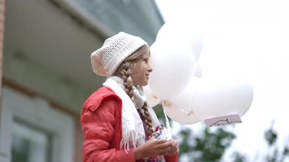 Side View Portrait Smiling Charming Teenage Girl Standing Outdoors Holding White Balloons with alt
