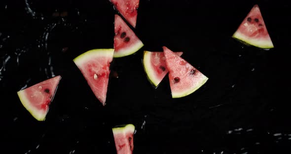 Pieces of Ripe Watermelon Fall on Water Splashes.  alt