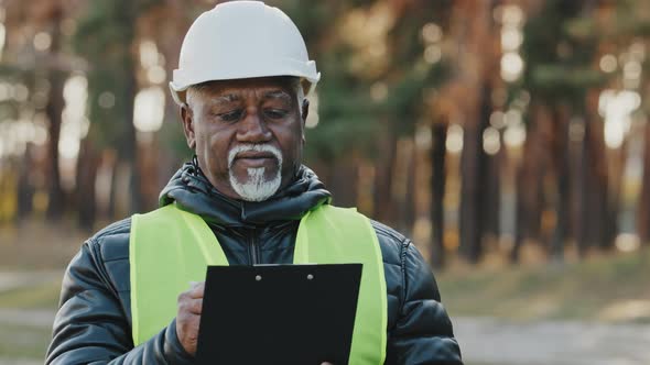 Mature Concentrated Forestry Engineer Technician Forester in Protective Helmet Stands in Park alt