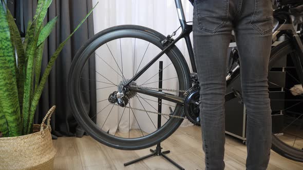 Mechanic takes bike off from rack in bicycle workshop. Repair bicycle in cycling workshop alt