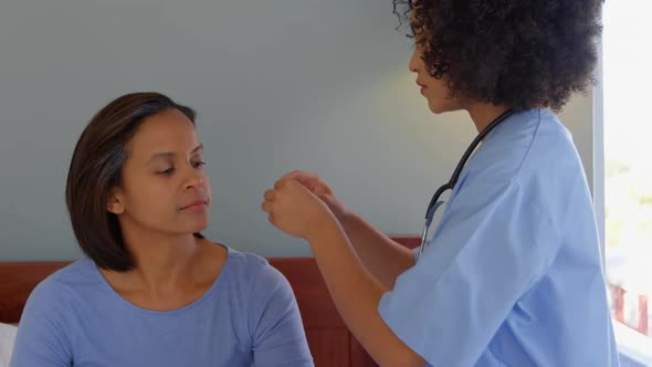 Mixed race female doctor inserting a hearing aid machine on womans ear at home 4k alt