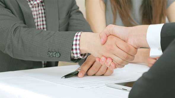 Three Businessmen Shaking Hands at the Table alt