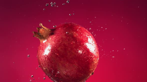 Flying of Pomegranate in Fuchsia Background in Slow Motion alt