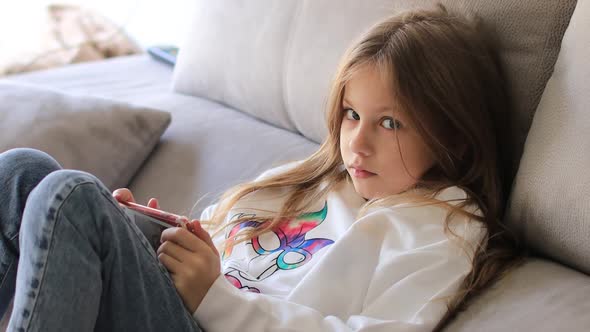School Girl in White Blouse 9 Years Old Playing Mobile Game on Phone