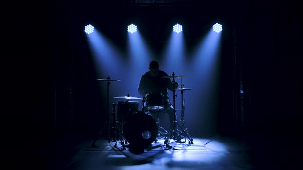 Silhouette Drummer Playing on Drum Kit on Stage in a Dark Studio with Smoke and Neon Lighting alt