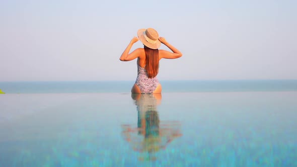 Young asian woman enjoy around outdoor swimming pool for leisure alt