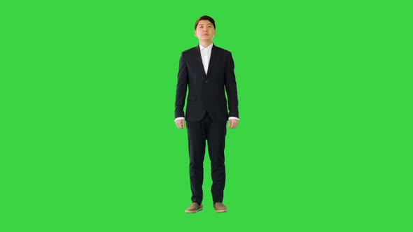 Asian Man Stands Adjusting His Suit and Crossing Arms on a Green Screen Chroma Key alt