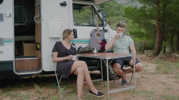 Travel Couple van drinking coffee near motorhome  while camping on road trip in Montenegro alt