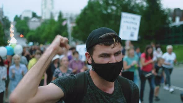Masked People on Anti Covid Restriction March Picket Activist Guy Wave Arm Fist