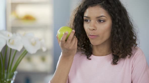 Multiracial Beautiful Woman Eating Apple at Table, Daydreaming, Happy Thoughts alt