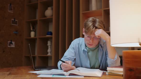 Young Man in Glasses Studying and Stressing in Warm Wood Room alt