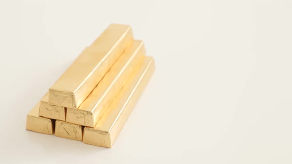 Lot of golden foil wrapped chocolate bars on white surface 4K 2160p UltraHD footage - Gold color pac alt