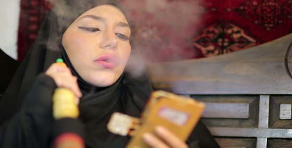 Woman With Chador Smoking Shisha and Using Mobile Phone alt
