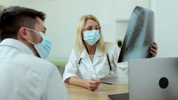 Medical Physician Doctor in Medical Mask Specialist Showing Xray Image of Lungs to Patient alt