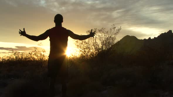 Male reaching his arms out at sunset alt