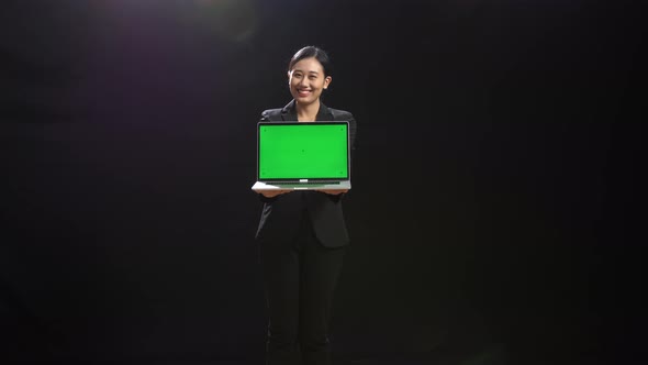 Asian Woman In Business Suit Holding Laptop Computer With Green Screen In The Black Screen Studio alt
