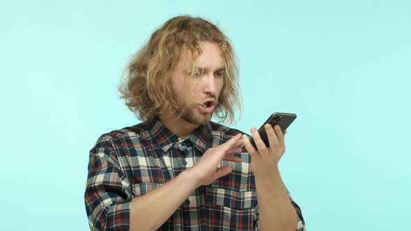Slow Motion of Serious Blond Man Talking on Speakerphone Holding Smartphone Near Mouth and Gesturing