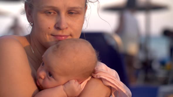 Wistful mother with baby on the beach at sunset alt