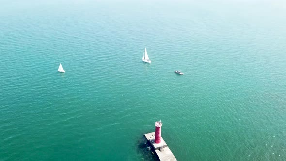 Aerial view of lake Michigan, drone flying around sailboats and lighthouse	