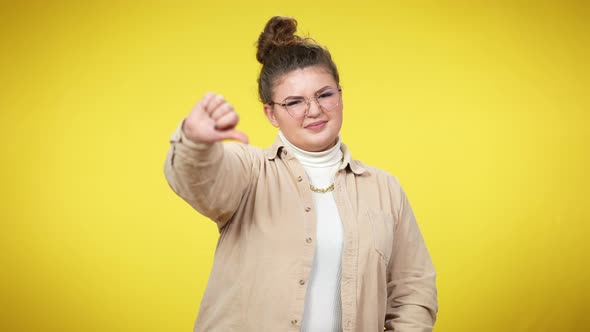 Young Confident Plussize Woman Showing Thumbs Down Posing at Yellow Background alt