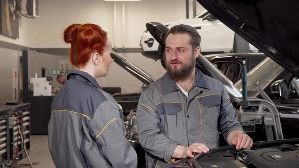 Bearded Mechanic Talking To His Female Coleague at the Automobile Workshop alt
