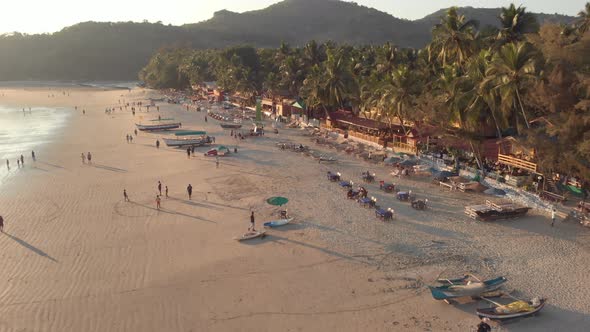 Drone footage of a beach at sunset in Palolem, India busy with visitors from all over the world alt