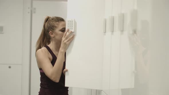 Young woman opening locker in gym changing room