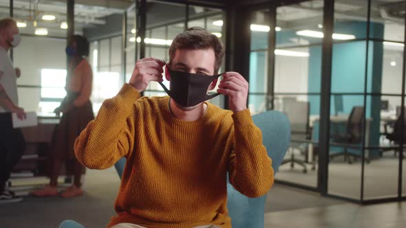 Sitting in the Entrance Hall in the University a Young Caucasian Student is Putting a Protective alt