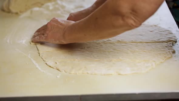 A Woman Prepares A Dough And Cuts It With A Knife On The Table