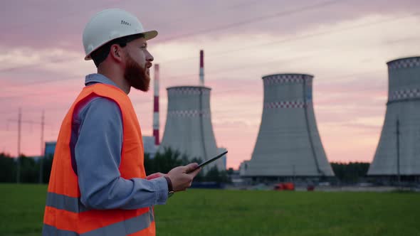 Engineer in a Helmet with a Tablet in His Hands Background of Power Grids alt