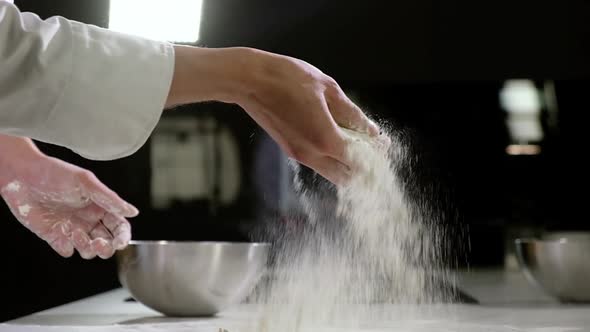 man sprinkles flour with hand on table for making dough for traditional pizza.