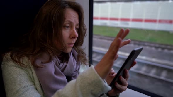 Adult Woman Is Going To Work By Suburban Train, Reading News in Internet By Smartphone alt