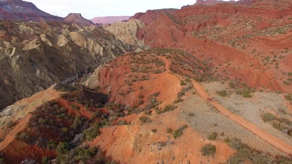 Aerial view following truck driving over winding dirt road on hill top alt